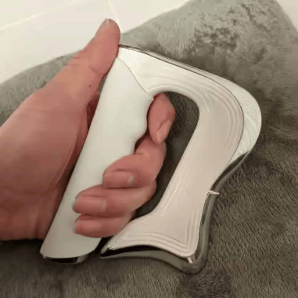 Hand holding a white electronic device on a gray surface