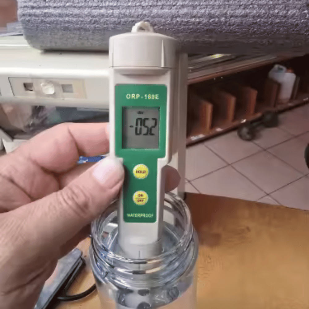Hand holding a digital ORP meter with a blurred background
