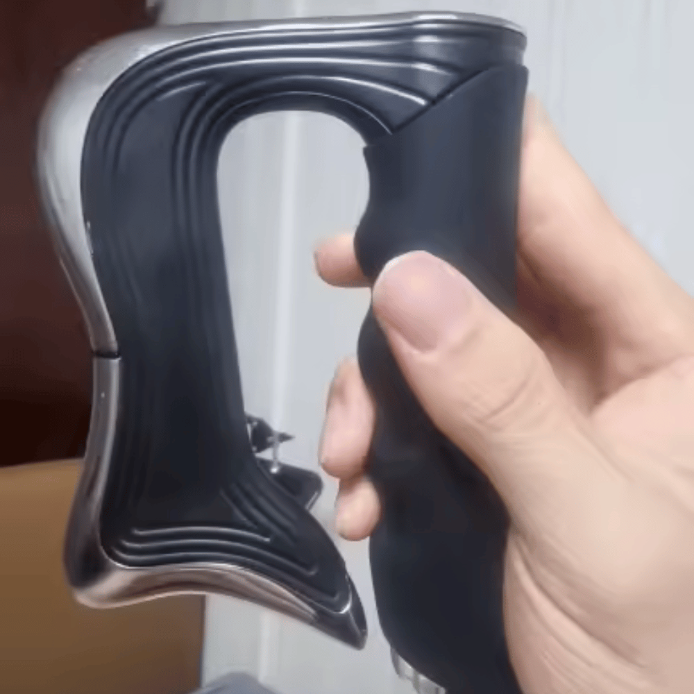 Hand holding a black and silver device with a textured grip