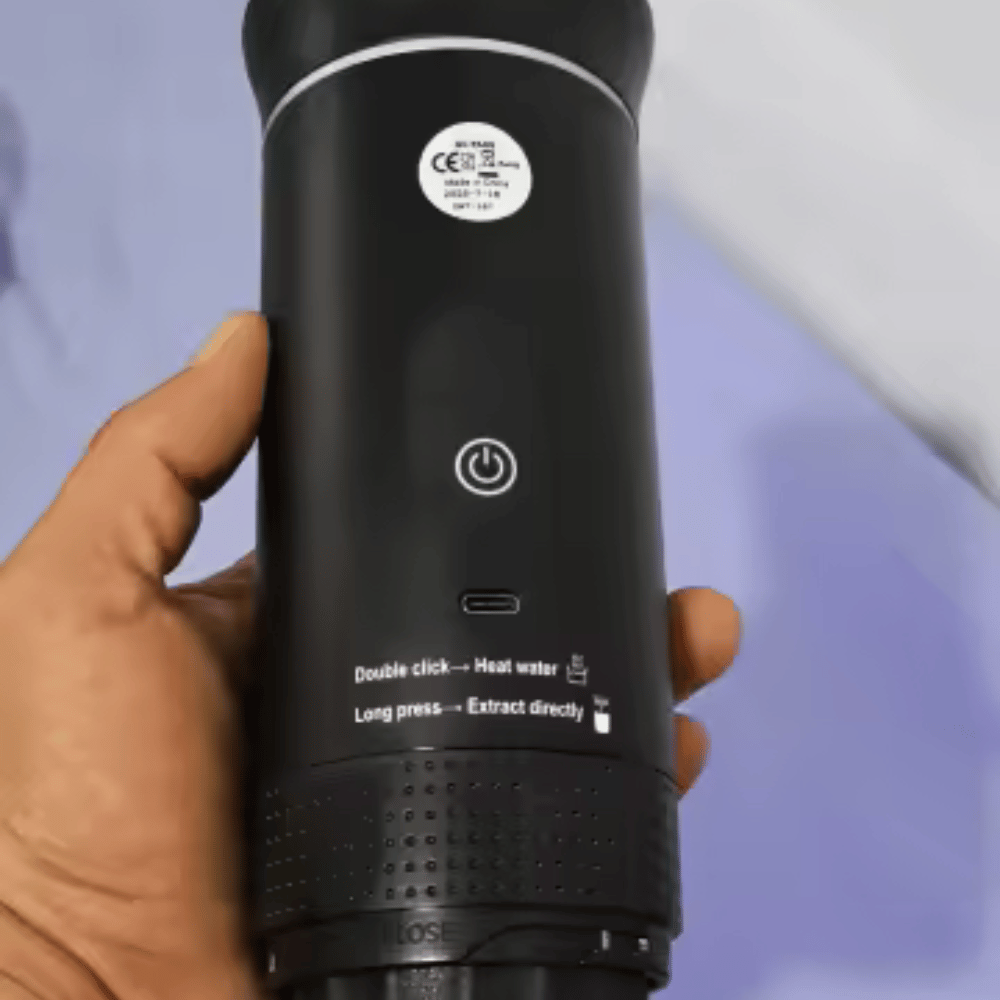 Black handheld device with control buttons held by a hand against a blurred background