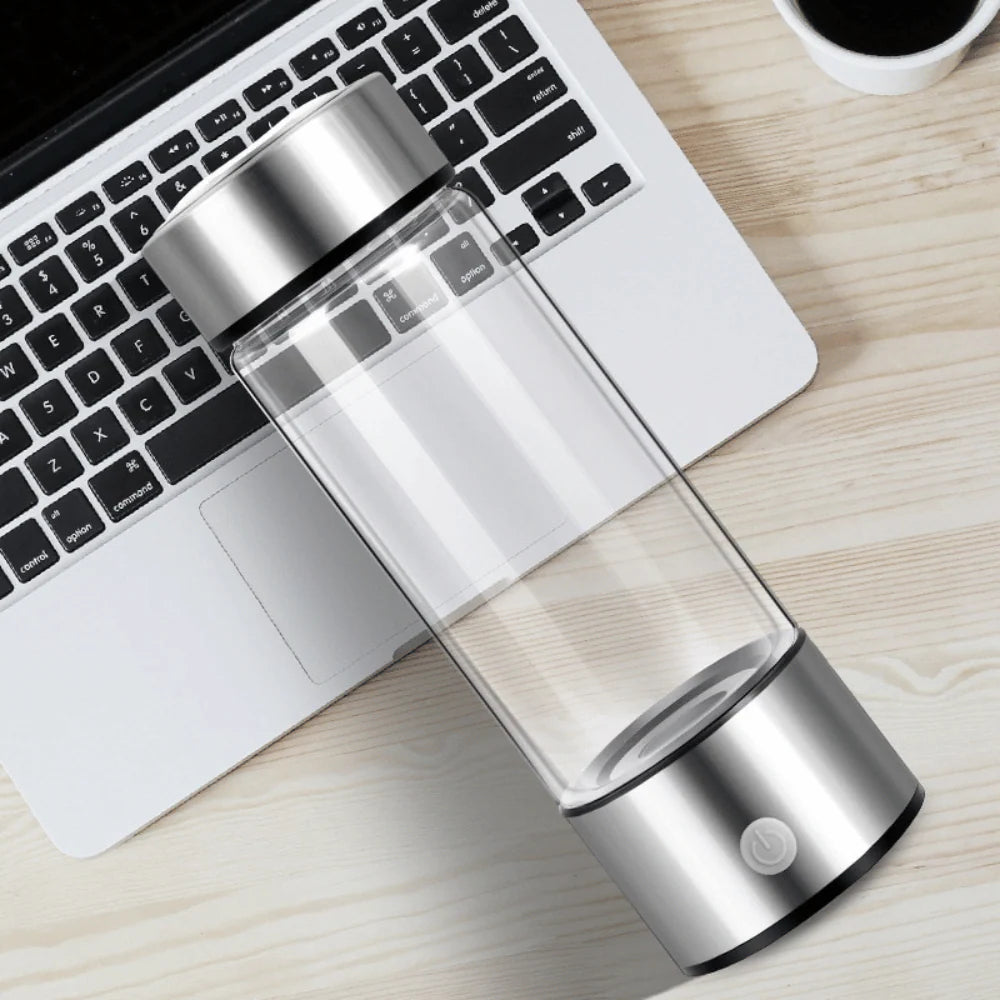 Portable hydrogen water bottle on laptop desk, stainless steel base and glass body for office and travel hydration