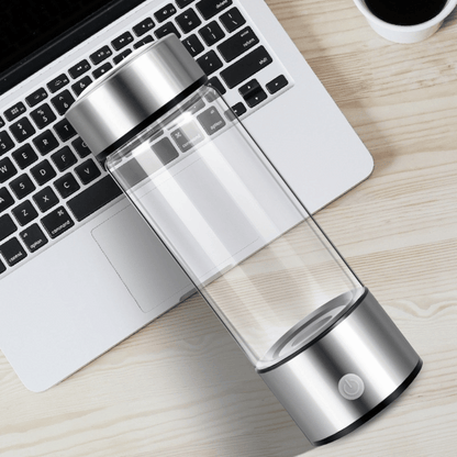 Clear and silver water bottle on a desk with a laptop and coffee cup in the background