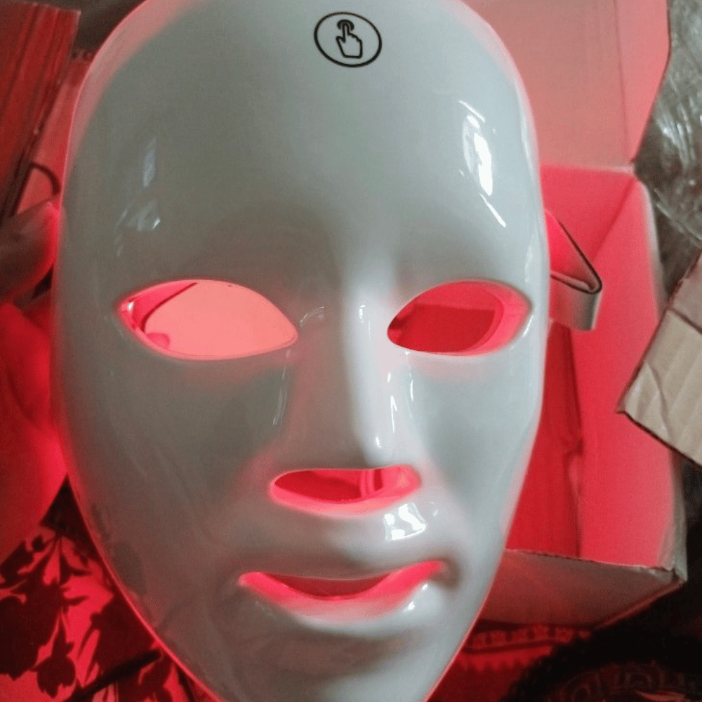 LED face mask with red and green lights on a neutral background